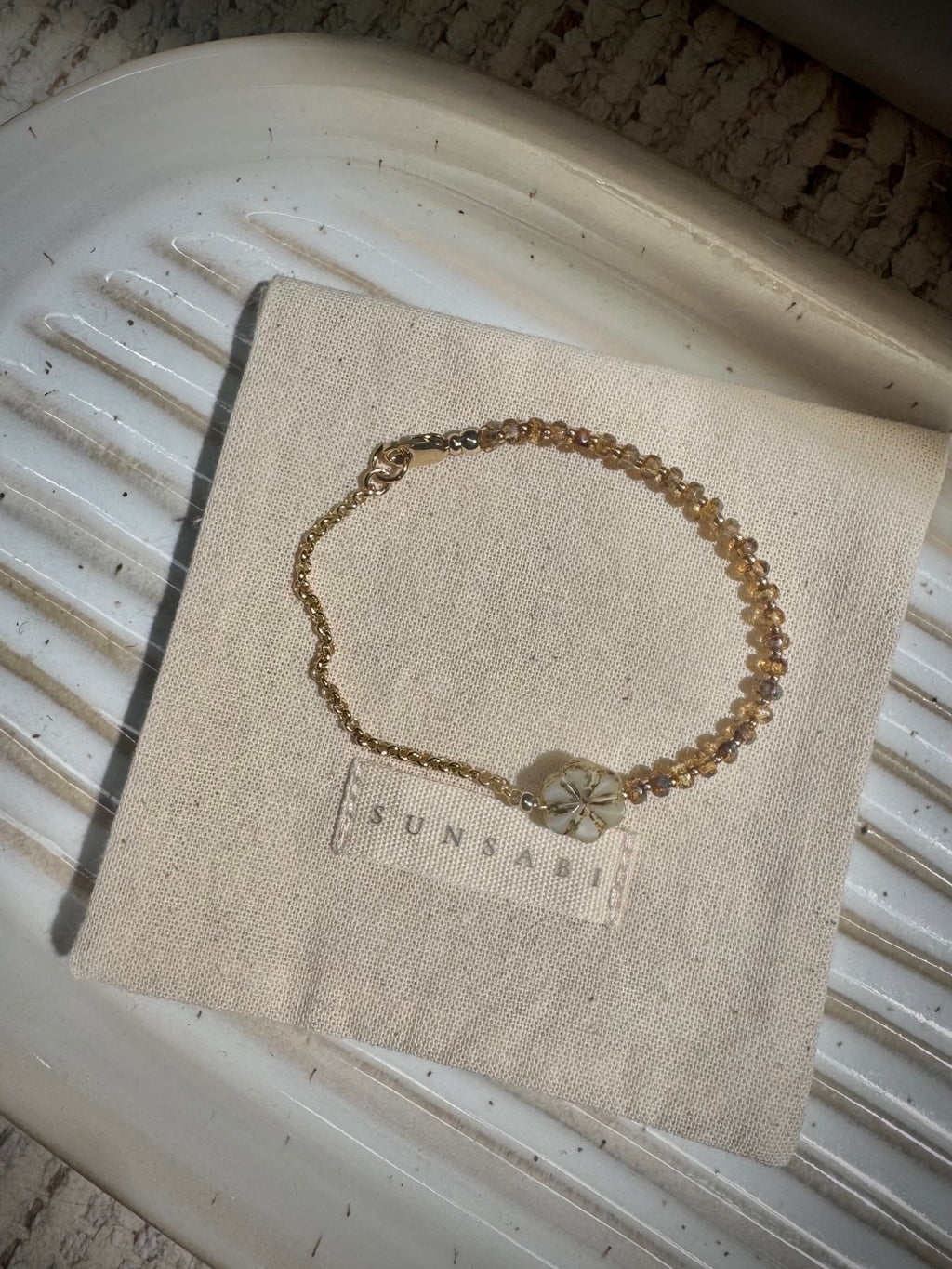 SUN BEAM handmade child bracelet displayed on natural linen with honey glass beads and gold-filled chain