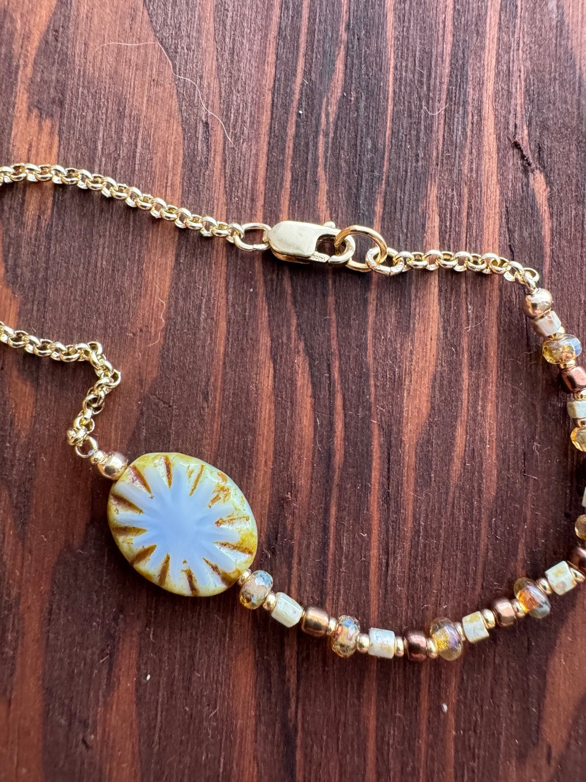 SUN BLOOM No. 02 bracelet showing the Czech glass bloom, gold-filled rolo chain and clasp on walnut timber