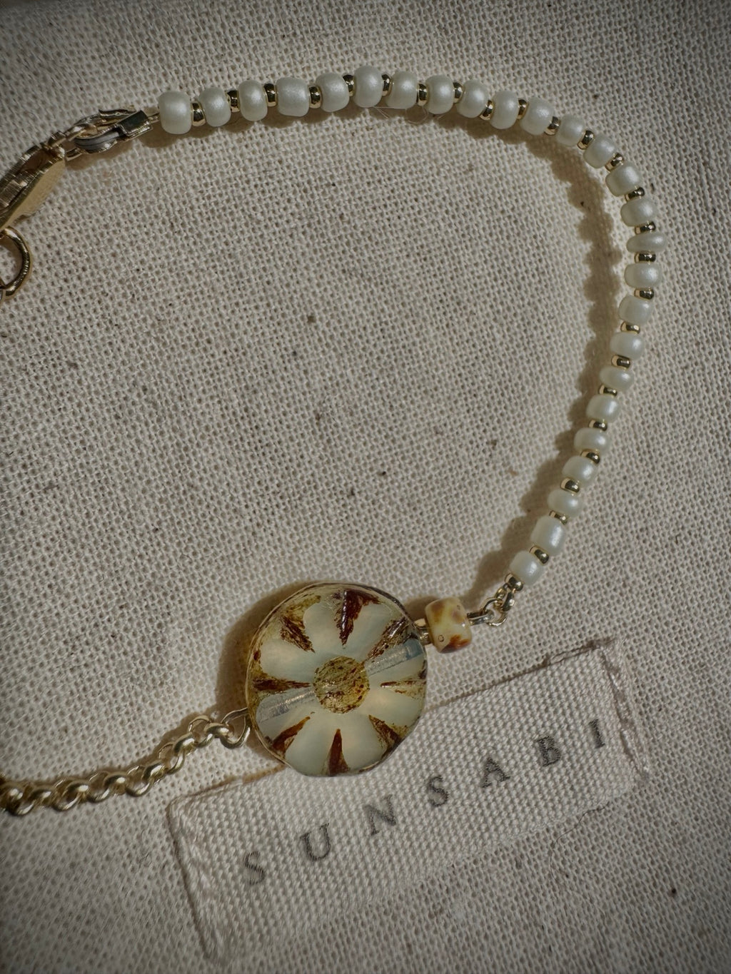 Detail of SUN BLOOM No. 03 ivory glass seed beads, gold-filled spacers and weathered Czech glass bloom