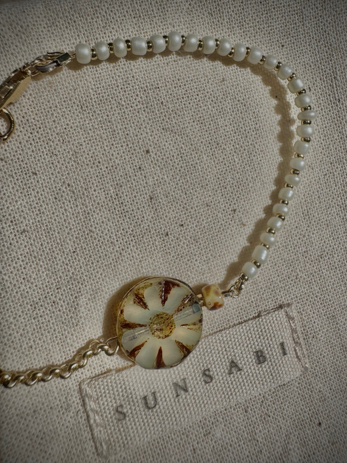 Detail of SUN BLOOM No. 03 ivory glass seed beads, gold-filled spacers and weathered Czech glass bloom