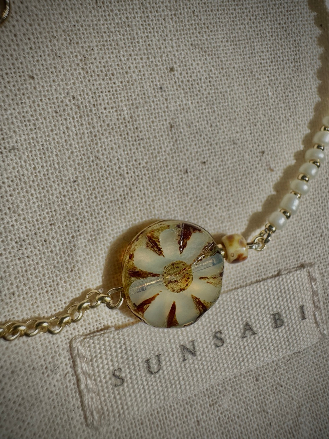 Close-up of the ivory Picasso Czech glass bloom, gold-filled rolo chain and glass bead details on SUN BLOOM No. 03